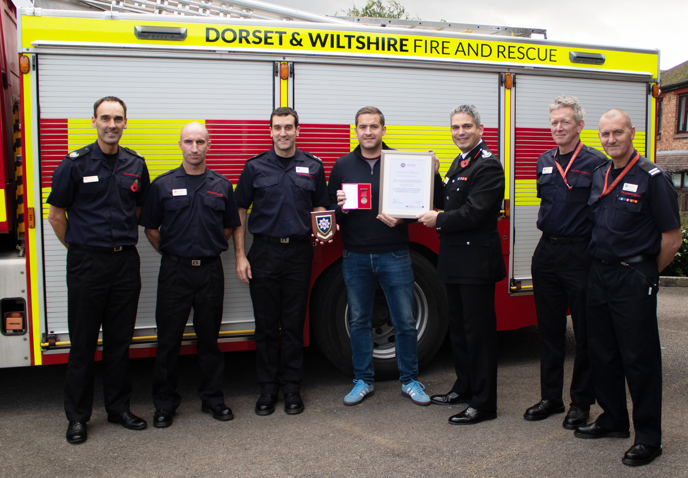 Chief Fire Officer Ben Ansell presents commendation and medal to Ben Howarth in front of the Royal Wootton Bassett fire crew