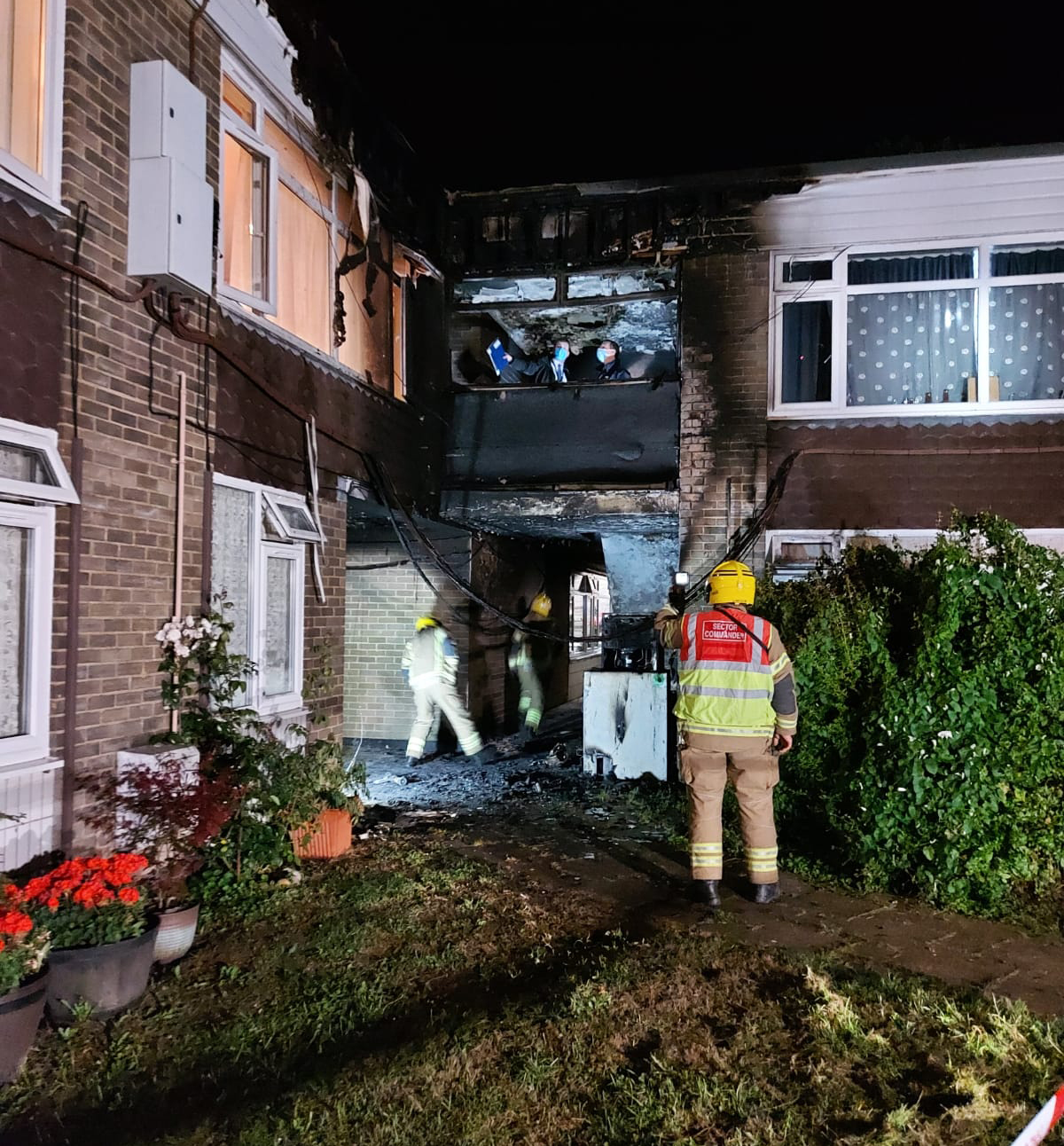 Outside of fire damaged property, firefighters checking it is safe